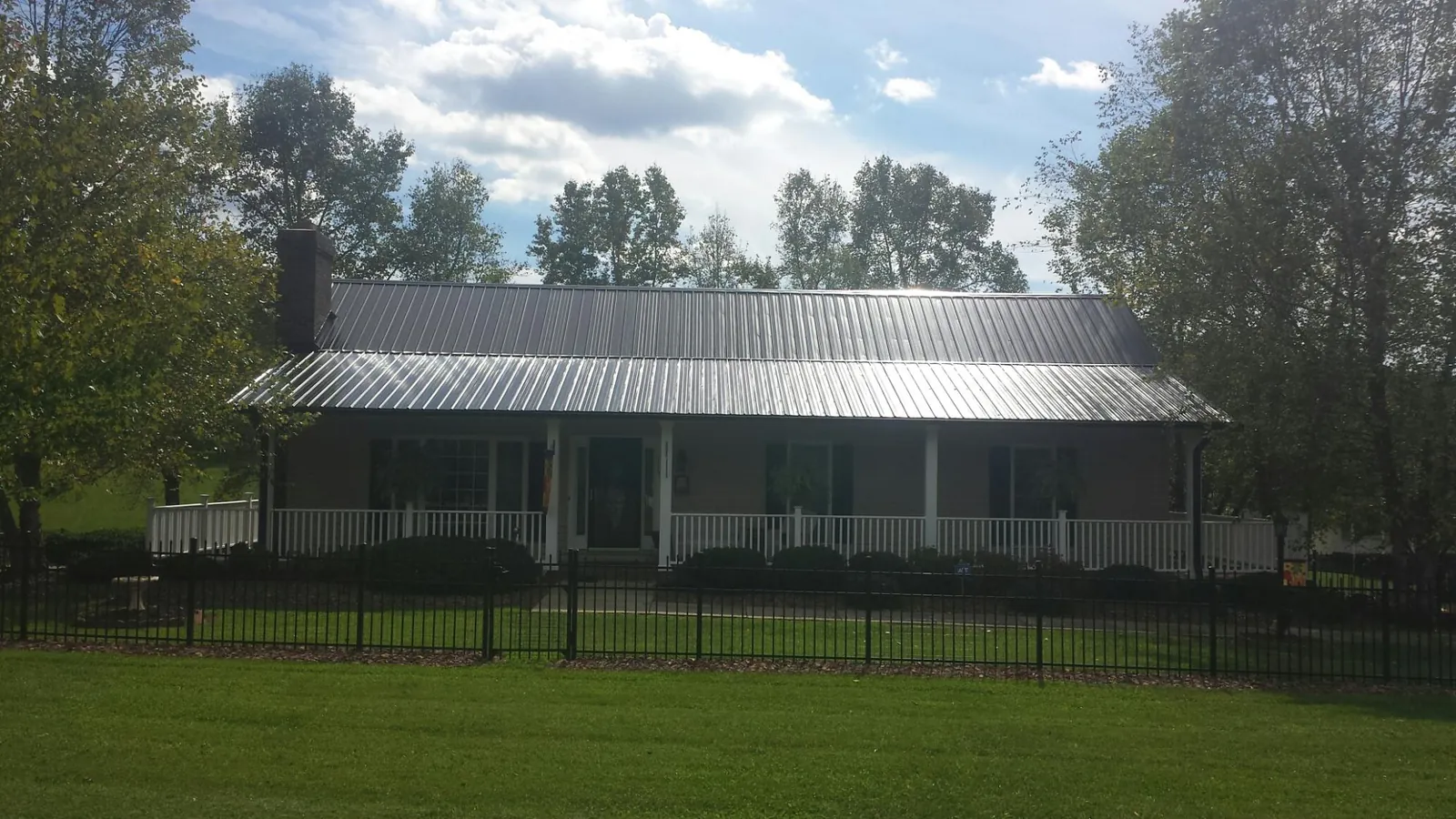 Gray metal roof on a brick ranch with a full width front porch — Gutter Guard Installation work by our crew in Rock Valley