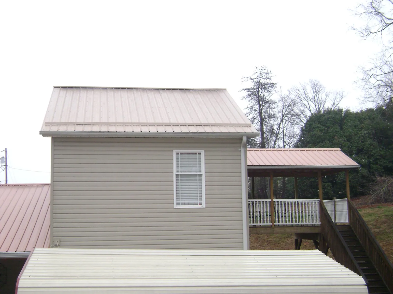 Tan metal roofs on a two story addition and attached porch, from a Roof Replacement job in Rock Valley