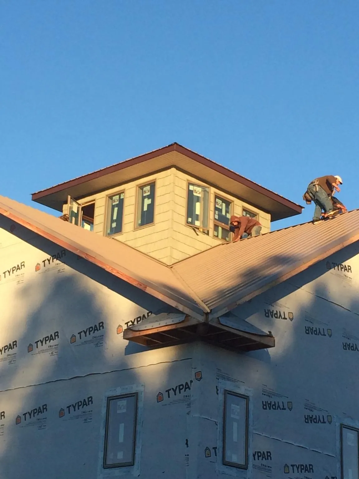 Roofers working around a rooftop cupola on a new metal roof at sunset — Roof Waterproofing in Rock Valley by Roofing Brothers
